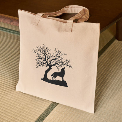 Howling wolf silhouette under a barren tree at dusk
